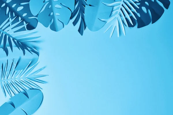 Frame of blue minimalistic paper cut palm leaves on blue background with copy space — Stock Photo