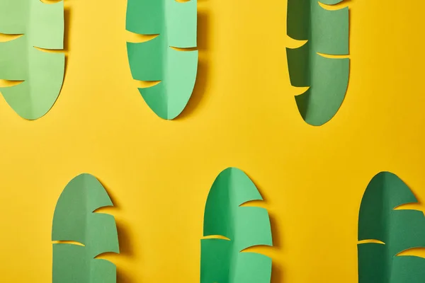 Vue du dessus des feuilles de palmier vert découpées sur fond jaune — Photo de stock