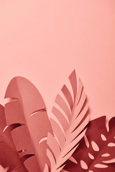 Vista superior de hojas de palma cortadas de papel decorativo sobre fondo rosa - foto de stock