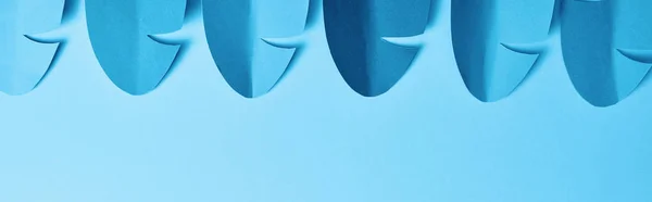 Panoramic shot of blue minimalistic paper cut palm leaves on blue background with copy space — Stock Photo