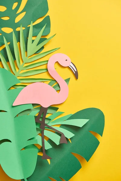 Top view of paper cut green palm leaves and cute pink flamingo on yellow background — Stock Photo