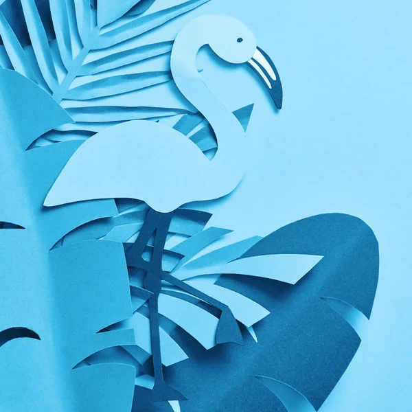 Vue du dessus des feuilles de palmier coupées en papier bleu et du flamant rose sur fond bleu — Photo de stock