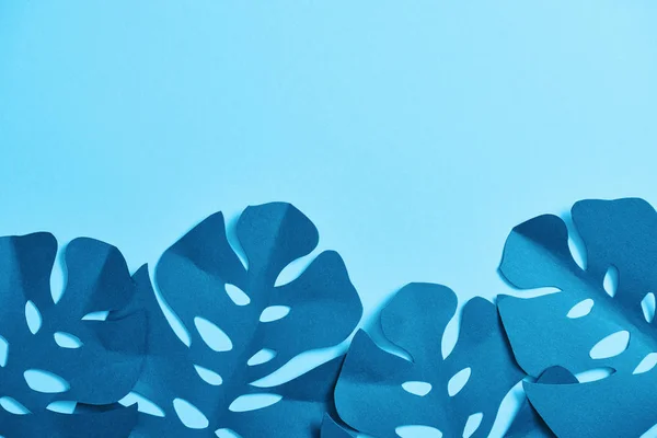 Top view of blue minimalistic paper cut palm leaves on blue background with copy space — Stock Photo