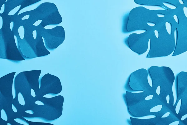 Vue du haut des feuilles de palmier bleu minimaliste en papier coupé sur fond bleu avec espace de copie — Photo de stock