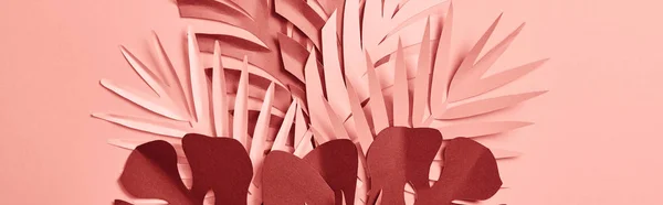 Панорамный снимок срезанной бумаги пальмовых листьев на розовом фоне — стоковое фото
