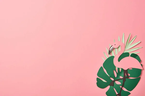 Vista superior de flamencos cortados en papel sobre hojas de palma verde sobre fondo rosa con espacio para copiar - foto de stock