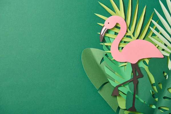 Top view of paper cut palm leaves and pink flamingo on green background with copy space — Stock Photo