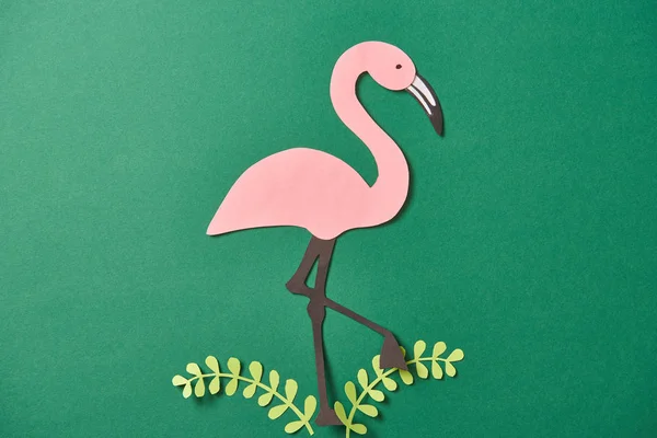 Vista superior de folhas de corte de papel e flamingo rosa no fundo verde — Fotografia de Stock
