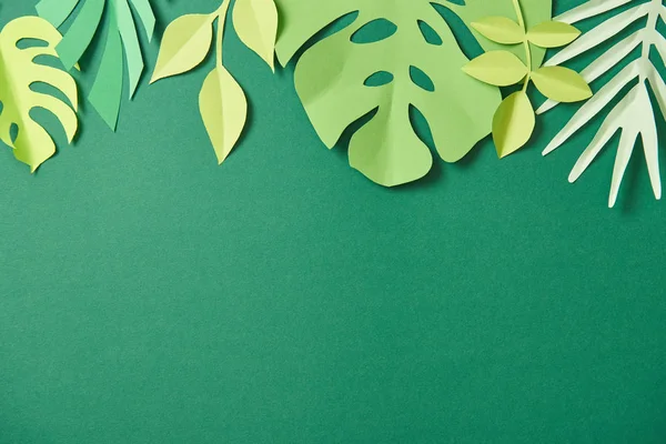 Top view of exotic paper cut palm leaves on green background with copy space — Stock Photo