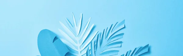 Top view of blue exotic paper cut palm leaves on blue background with copy space, panoramic shot — Stock Photo