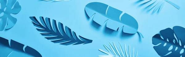 Vue du dessus des feuilles de palmier découpées en papier exotique bleu sur fond bleu avec espace de copie, vue panoramique — Photo de stock