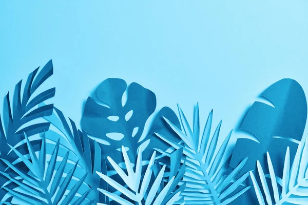 Top view of blue exotic paper cut palm leaves on blue background with copy space — Stock Photo