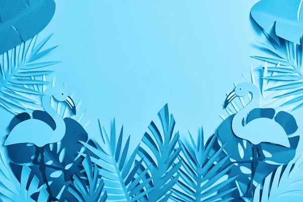 Vue du dessus de feuilles de palmier et de flamants roses découpés en papier exotique bleu sur fond bleu avec espace de copie — Photo de stock
