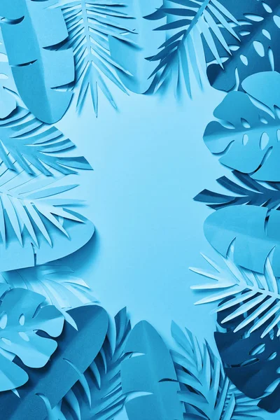 Top view of blue exotic paper cut palm leaves on blue background with copy space — Stock Photo