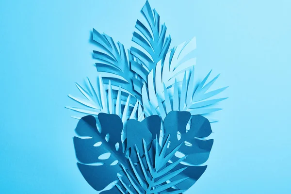 Vue du dessus des feuilles de palmier découpées en papier exotique bleu sur fond bleu avec espace de copie — Photo de stock