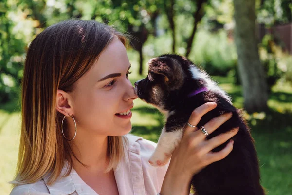 Happy blonde girl looking at cute puppy in green garden — Stock Photo