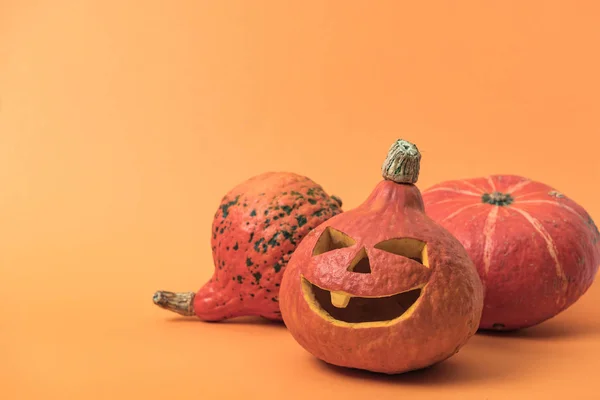 Gruselige Halloween-Kürbisse auf orangefarbenem Hintergrund mit Kopierraum — Stockfoto