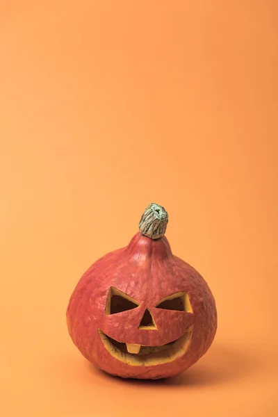 Spooky Halloween pumpkin on orange background with copy space — Stock Photo