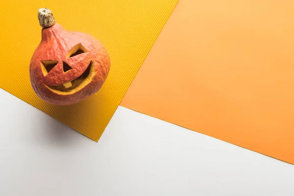 Top view of carved spooky pumpkin on white and orange background — Stock Photo