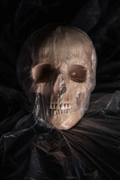 Teschio umano spettrale in cellophane su sfondo nero, decorazione di Halloween — Foto stock