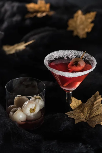 Red cocktail near maple dry yellow leaves on black background — Stock Photo