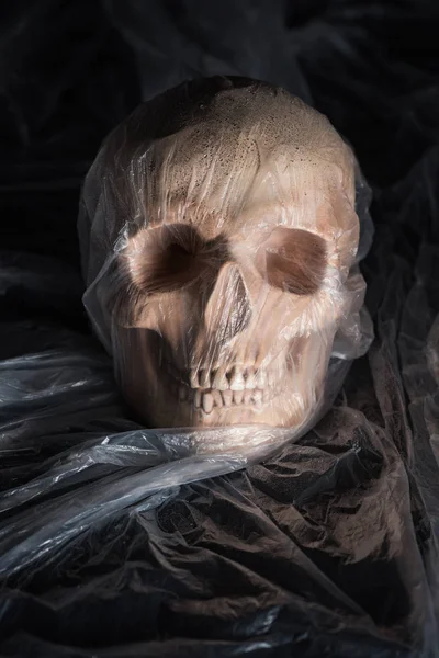 Spooky skull in cellophane on black background, Halloween decoration — Stock Photo