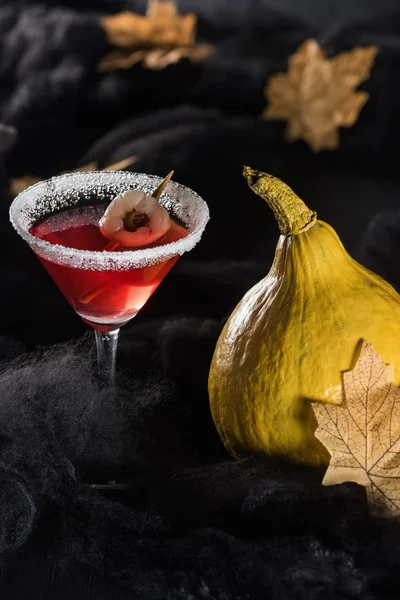 Ripe pumpkins near cocktail and maple dry yellow leaves on black background — Stock Photo