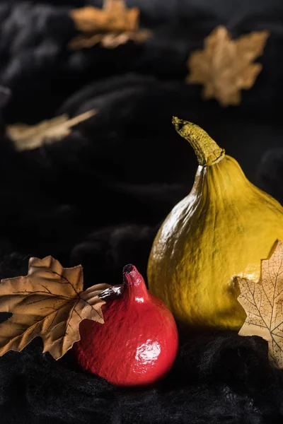 Ripe pumpkins near maple dry yellow leaves on black background — Stock Photo