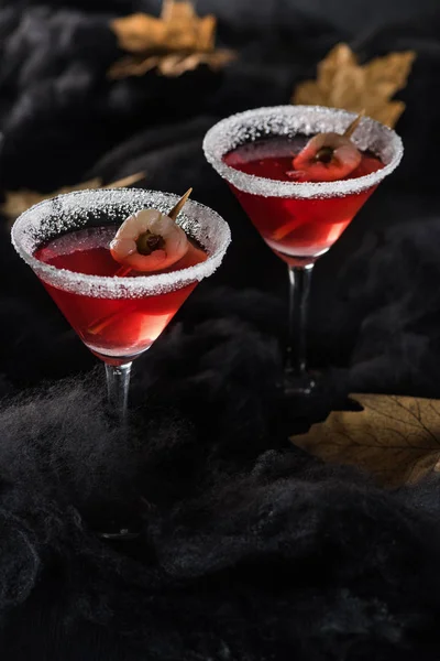 Red cocktails near maple dry yellow leaves on black background — Stock Photo