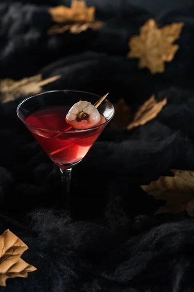 Red cocktail with maple dry yellow leaves on black background — Stock Photo