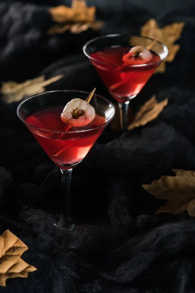 Red cocktails with maple dry yellow leaves on black background — Stock Photo