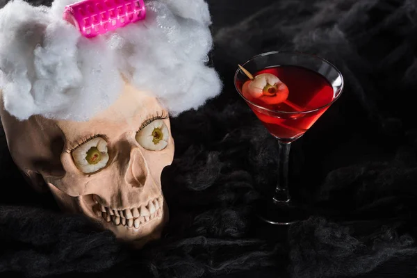 Red cocktail near decorated spooky skull on black background — Stock Photo