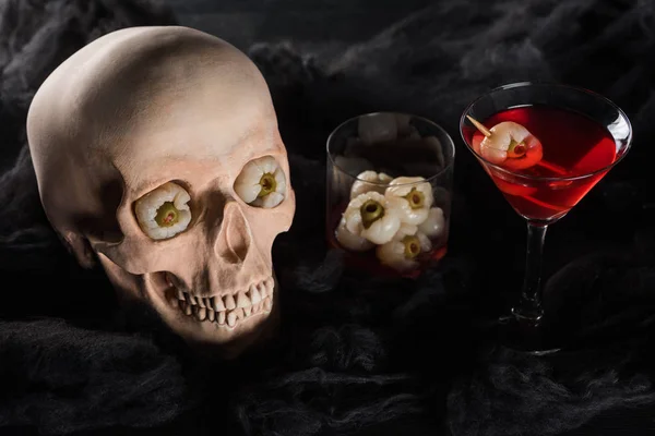 Red cocktail near creepy skull on black background — Stock Photo