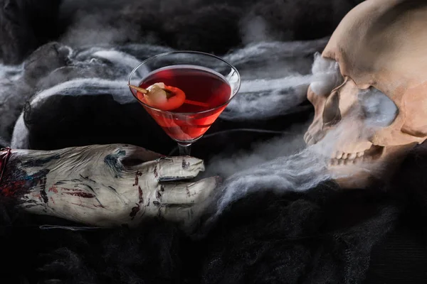 Crânio humano assustador com coquetel vermelho no fundo preto, decoração de Halloween — Fotografia de Stock