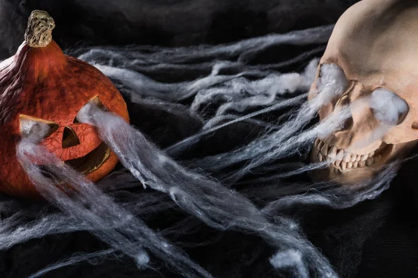 Effrayant crâne humain et sculpté citrouille Halloween sur fond noir — Photo de stock