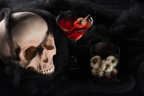 Spooky skull with red cocktail on black background, Halloween decoration — Stock Photo