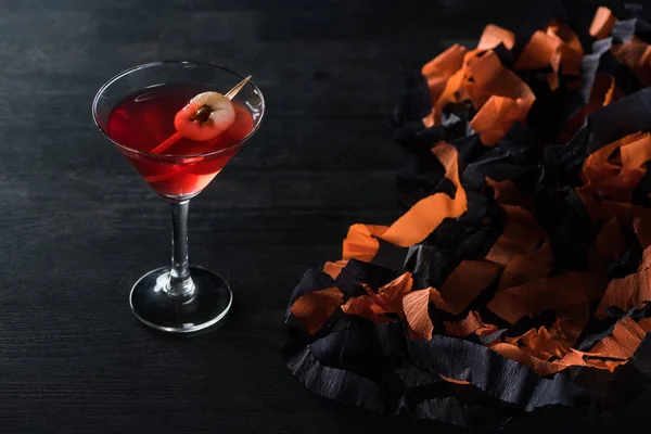 Cocktail savoureux rouge près de décoration Halloween sur fond noir — Photo de stock