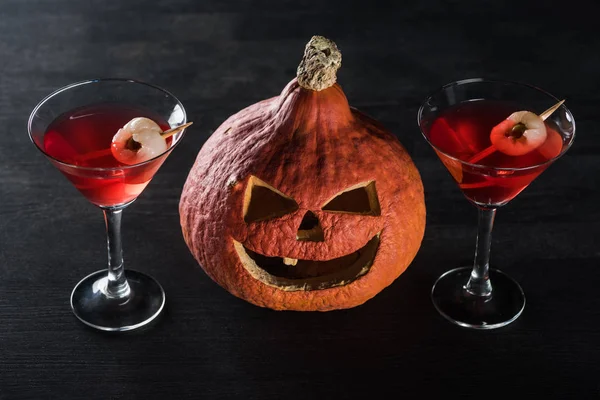 Gruseliger Halloween-Kürbis und rote Cocktails auf schwarzem Hintergrund — Stockfoto