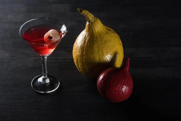 Ripe pumpkins and red cocktail on black background — Stock Photo