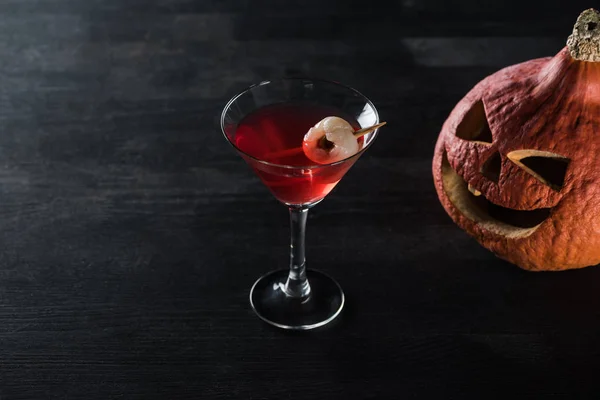 Geschnitzter Halloween-Kürbis und roter Cocktail auf schwarzem Hintergrund — Stockfoto