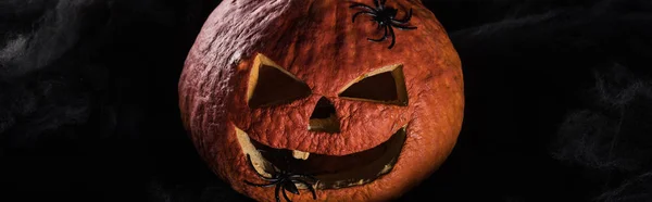 Panoramic shot of spooky carved Halloween pumpkin on black background — Stock Photo