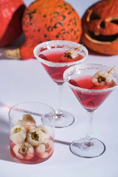 Rote Halloween-Cocktails mit Dekoration in Gläsern auf weißer Oberfläche — Stockfoto