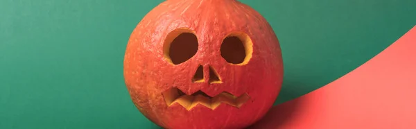 Plano panorámico de espeluznante calabaza de Halloween sobre fondo rojo y verde - foto de stock