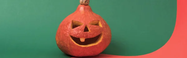 Panoramic shot of spooky Halloween pumpkin on red and green background — Stock Photo