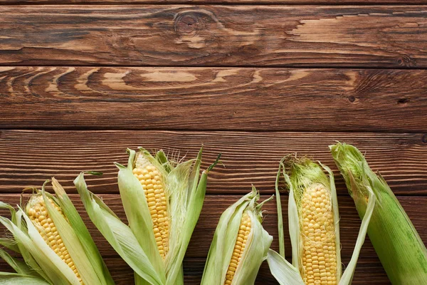 Top view of corn on brown wooden surface with copy space — Stock Photo