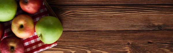 Panoramic shot of checkered tablecloth with fresh apples on wooden surface with copy space — Stock Photo