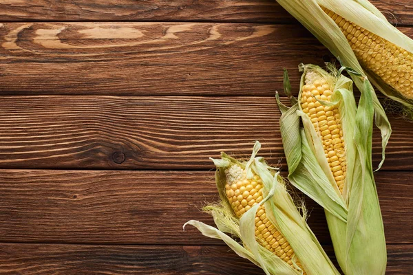 Top view of fresh corn on wooden surface — Stock Photo