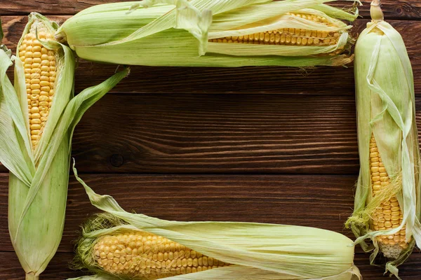 Top view of frame of fresh corn on brown wooden surface — Stock Photo