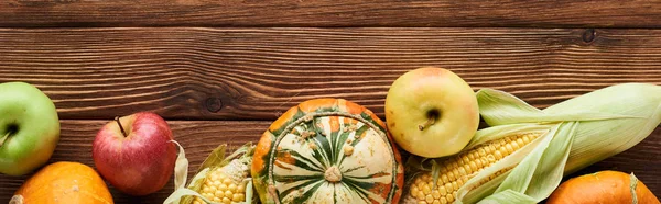 Coup panoramique de pommes fraîches, de citrouilles et de maïs sucré sur une surface en bois — Photo de stock