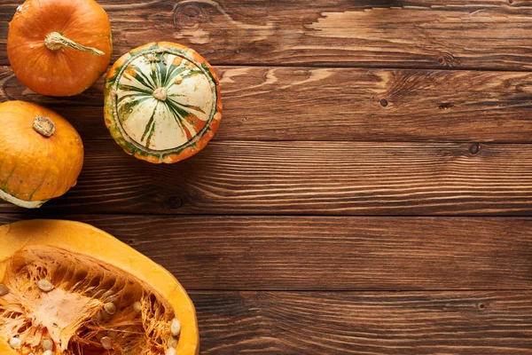 Top view of fresh whole and half of pumpkin on brown wooden surface — Stock Photo